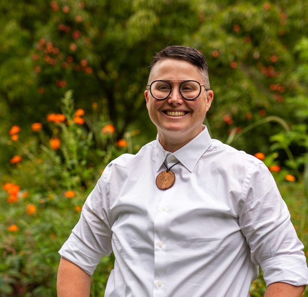 iMAGE OF A WHITE BUTCH LAUGHING IN FRONT OF FLOWERS. 